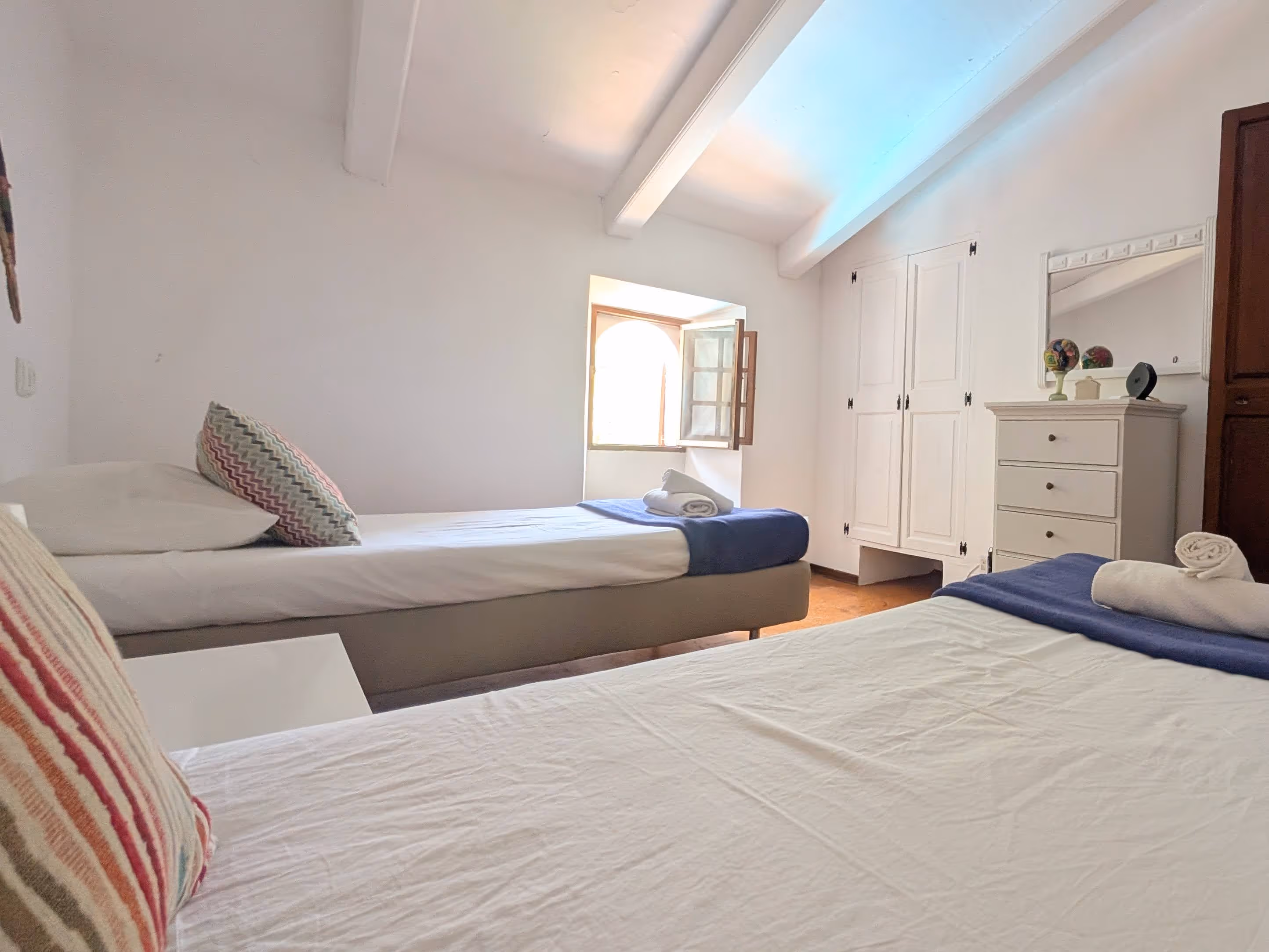 Double room with two single beds, a window, and exposed wooden ceiling beams.