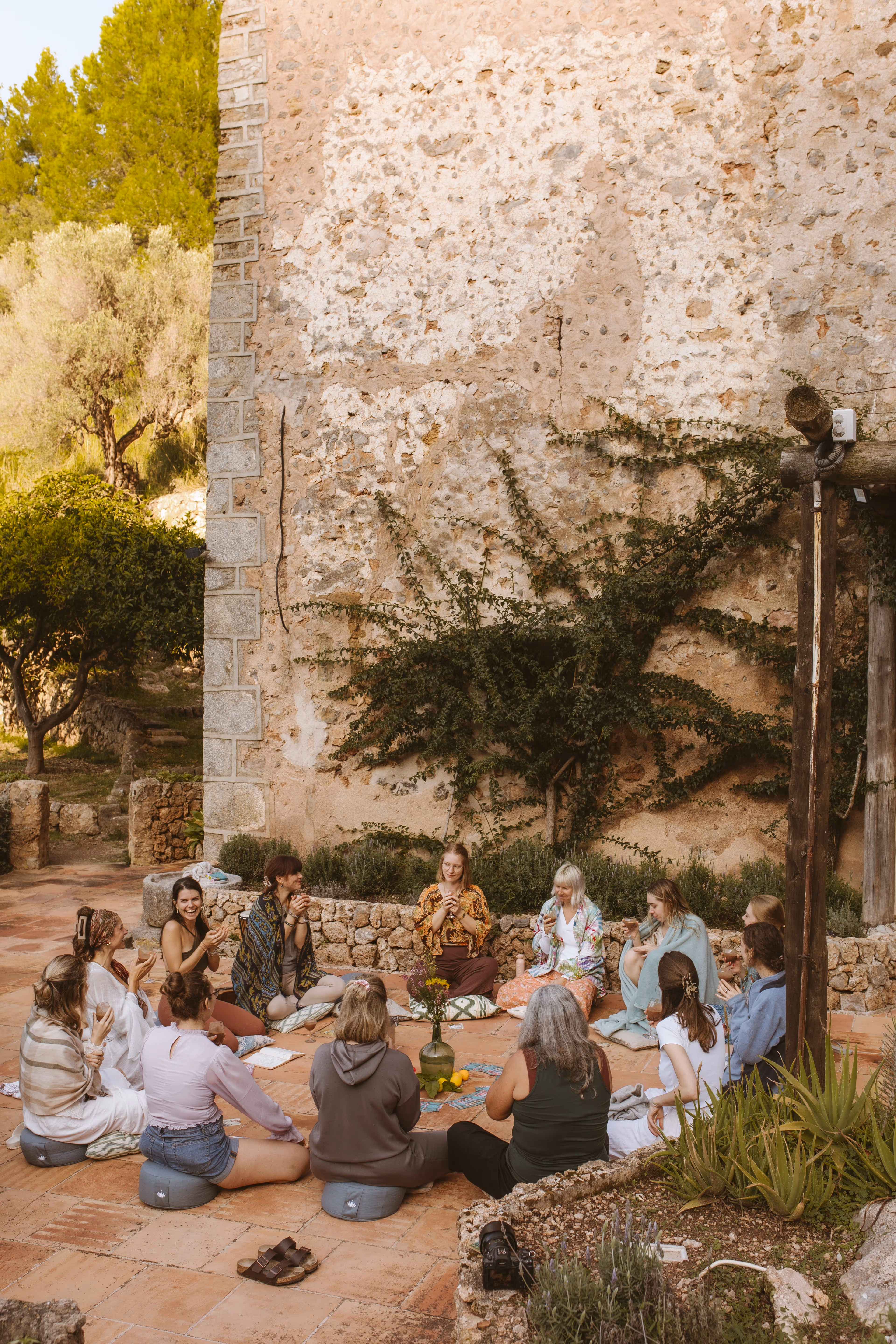 Finca Higo retreat participants sitting in a sharing circle in a stone courtyard surrounded by nature.