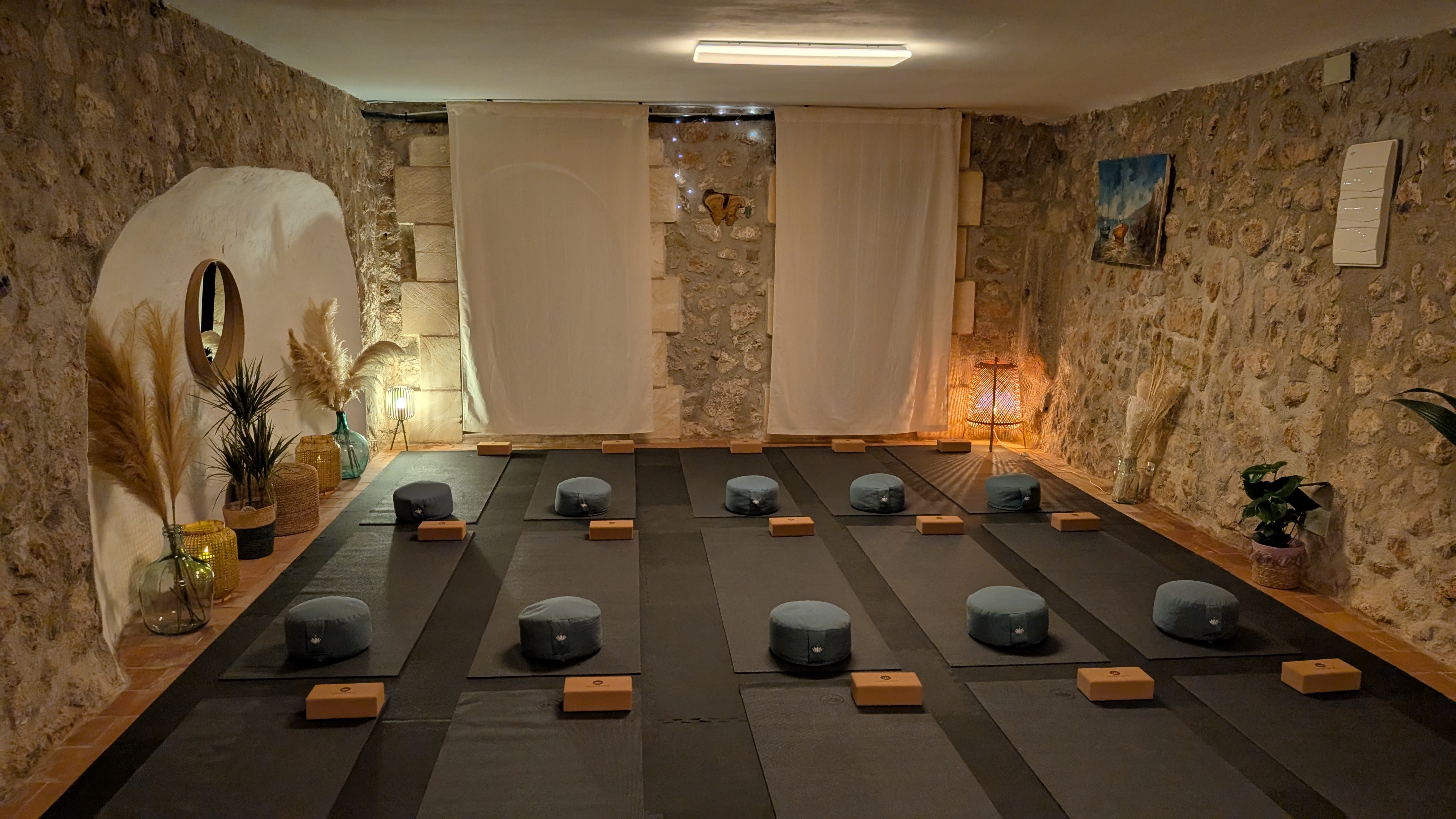 View inside the yoga room with yoga mats, blocks, bolsters, and cushions prepared for a group session.