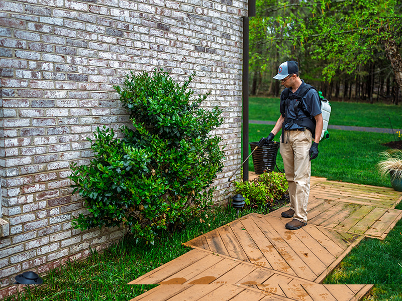 pest technician treating outside of home