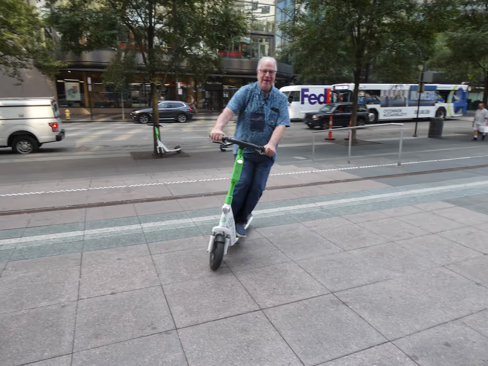 Man riding an electric scooter on the sidewalk