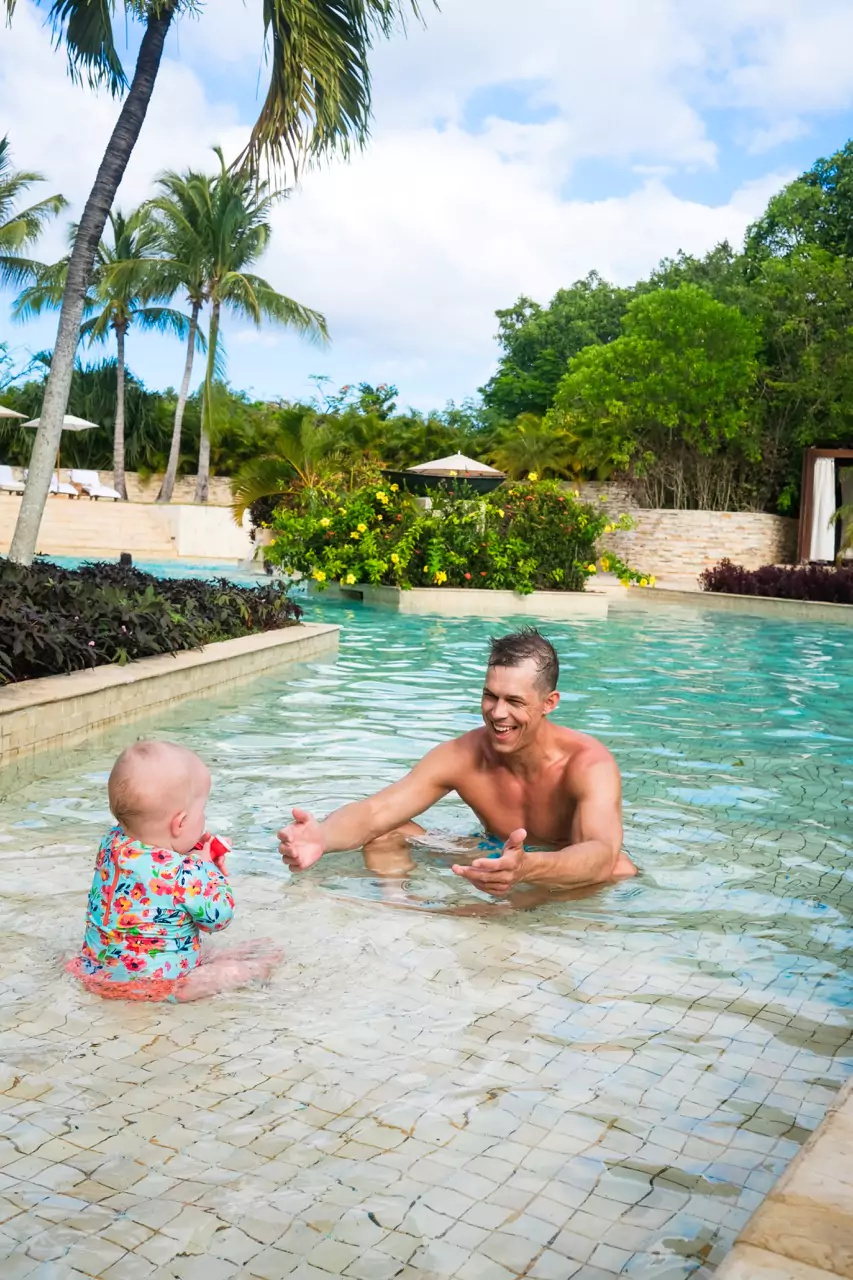 A baby and dad sitting in a shallow pool at Rosewood Mayakoba