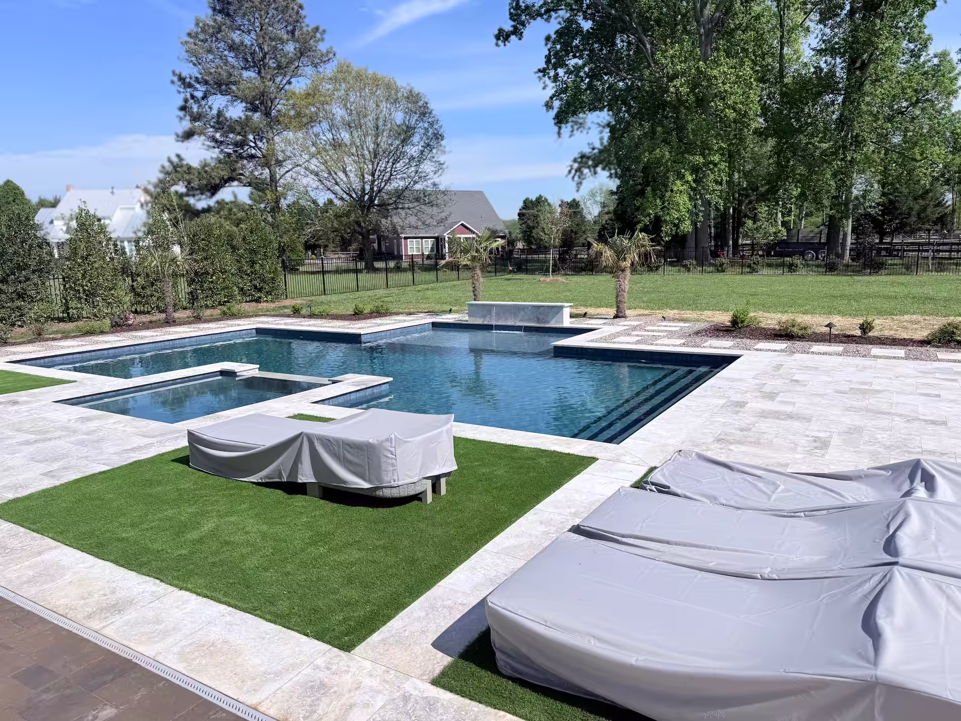 Luxury pool design with white tiles and turf.