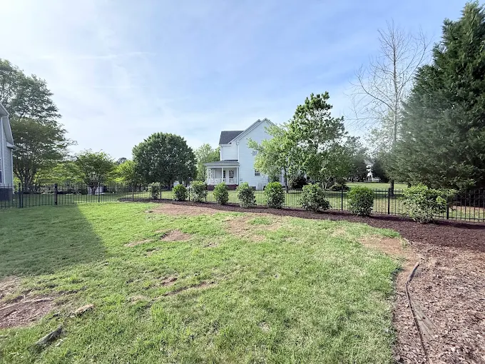 Trimmed lawn, mulch, and bush installation.