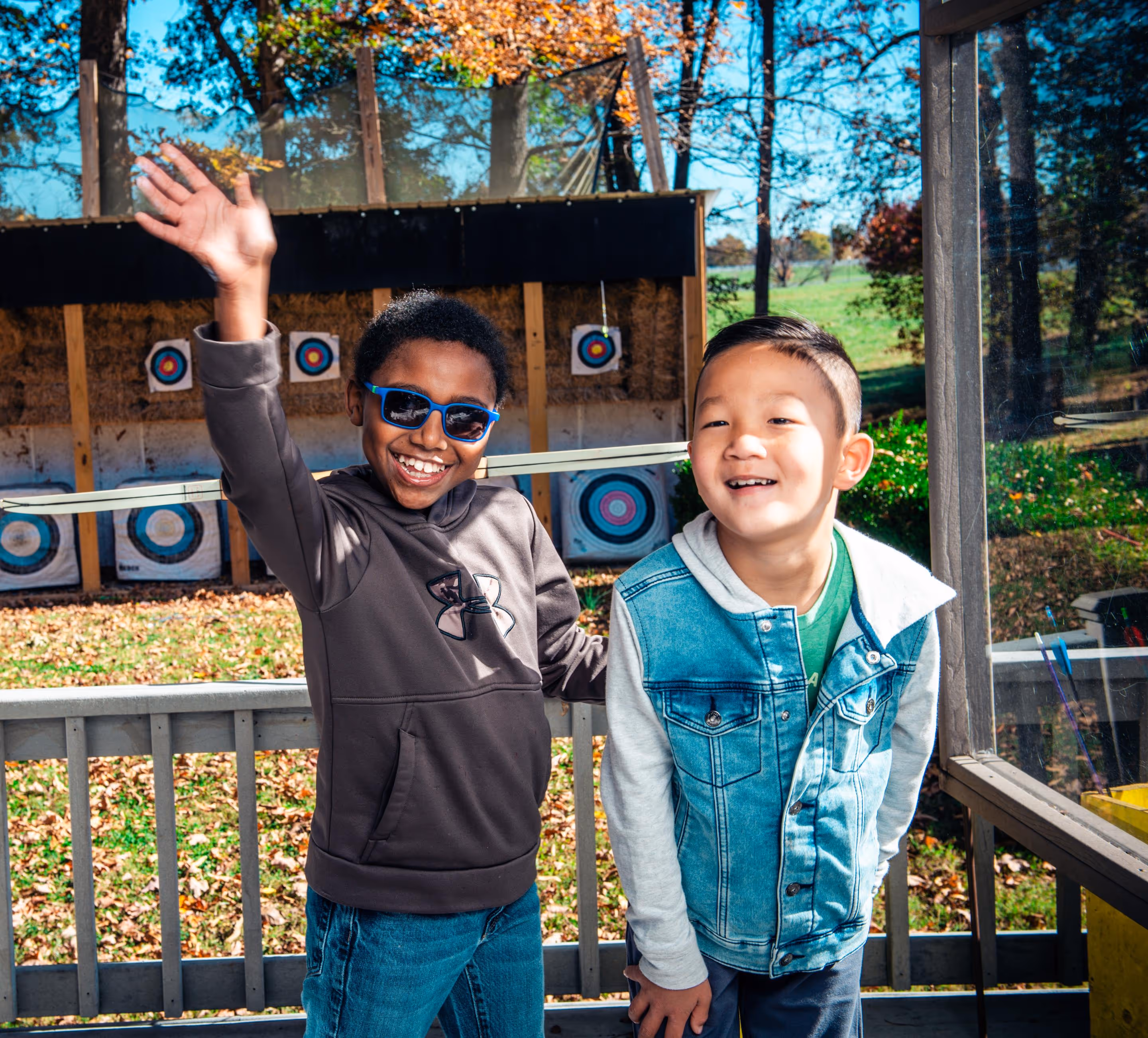 Two boys waving in front of archery range