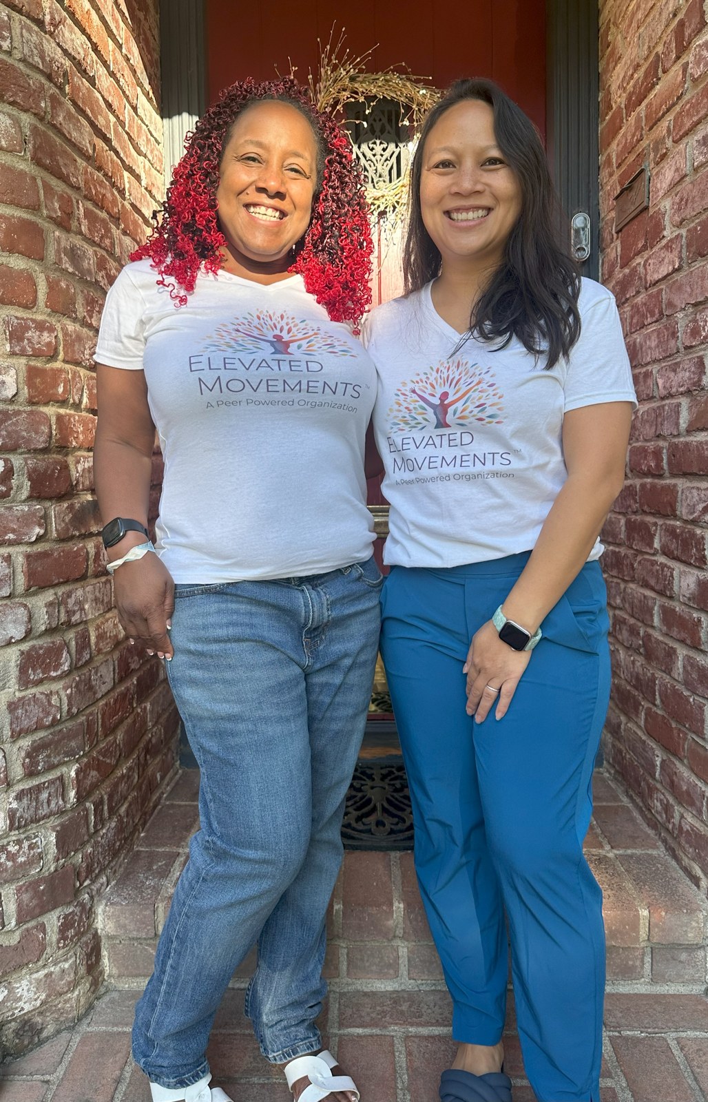 Two women smiling outside in Elevated Movements T-shirts.