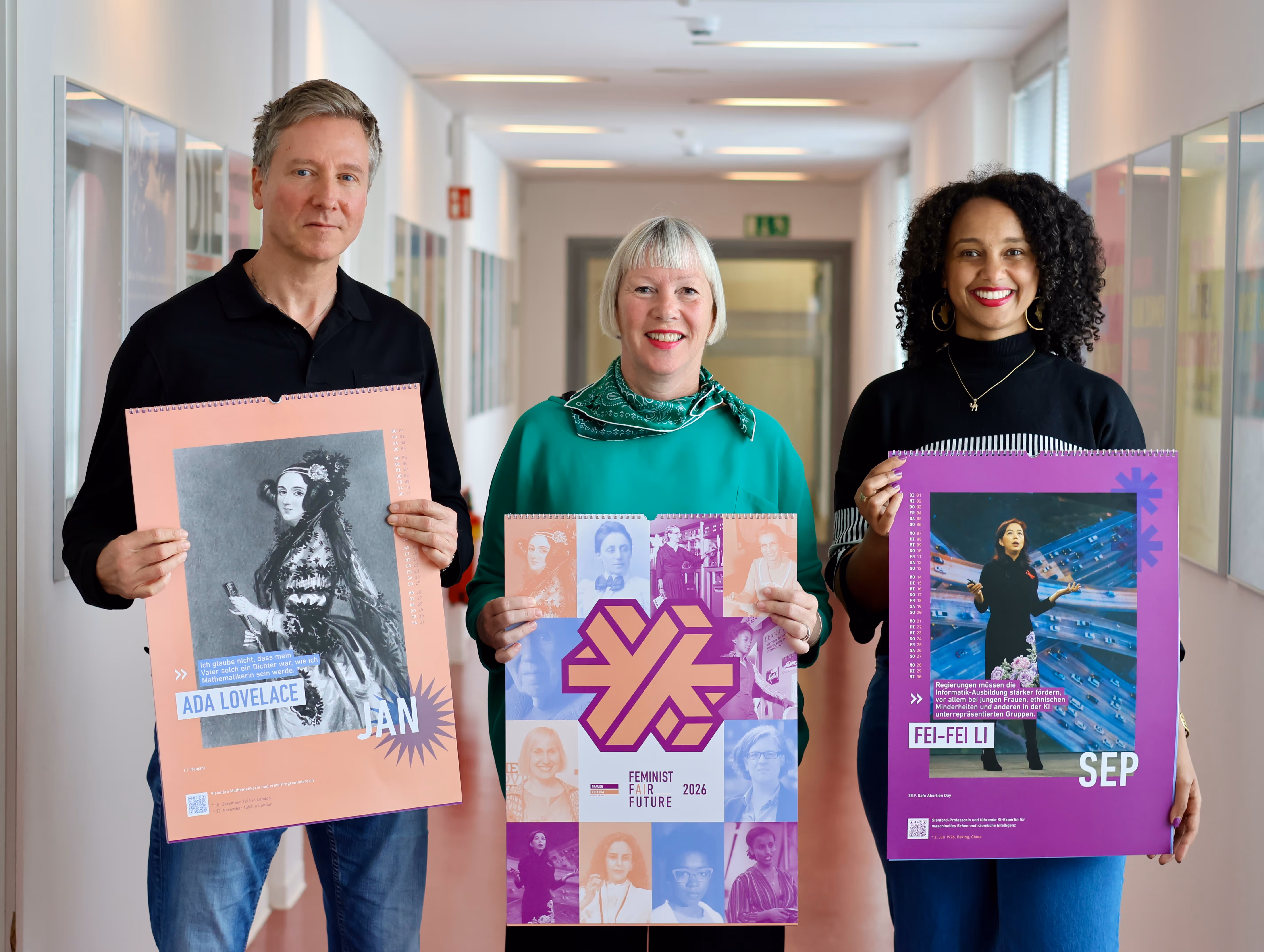 3 Personen halten den Jahreskalender und lächeln.