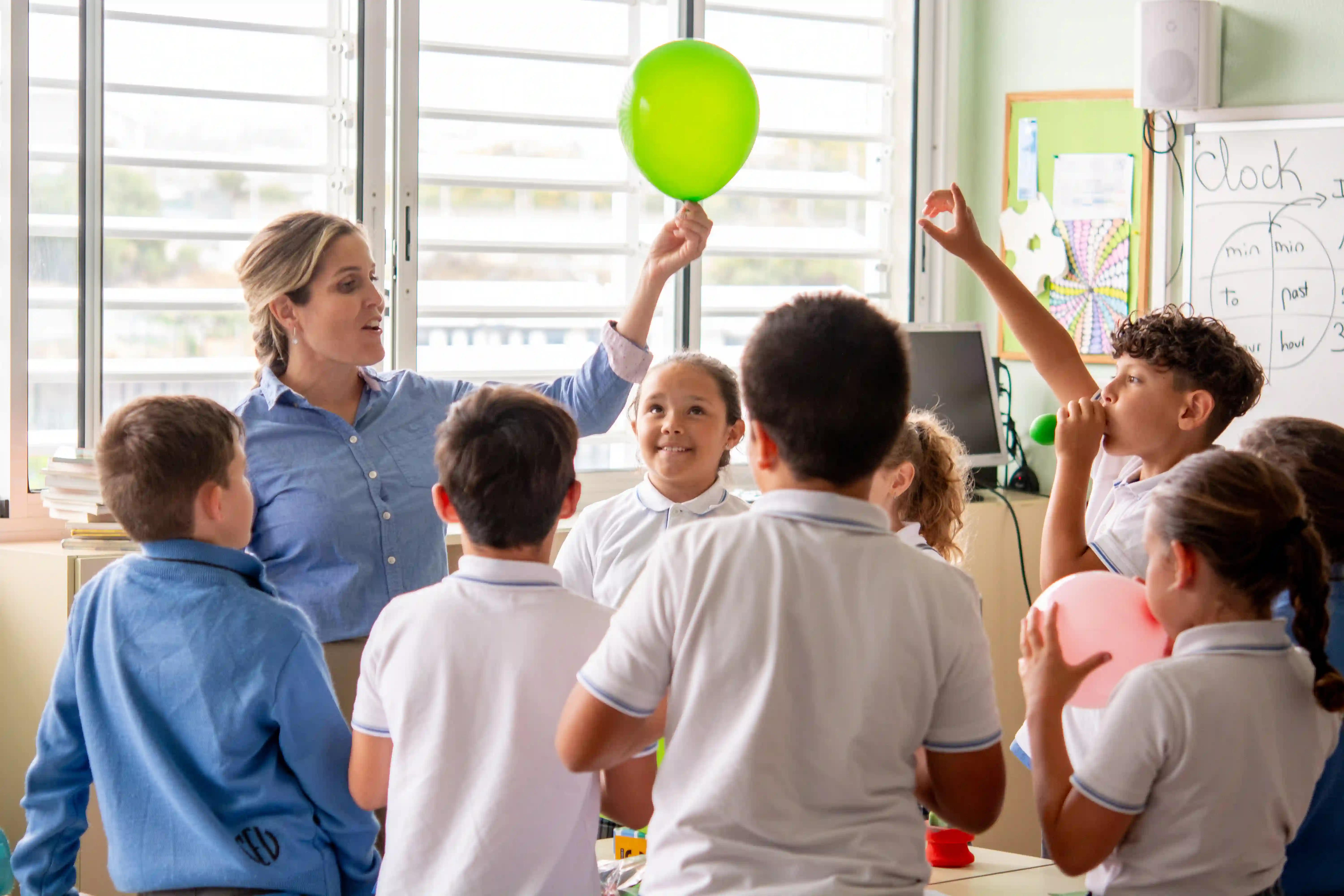 Teacher and young students holding balloons in a classroom