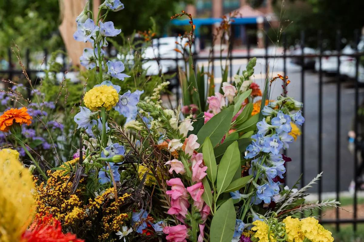 Vases of blue, pink, and yellow flowers fill a vendor's tent.