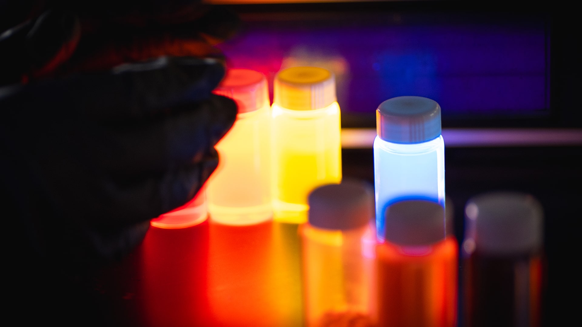 Quantum dot materials glowing under UV light in the UbiQD lab.