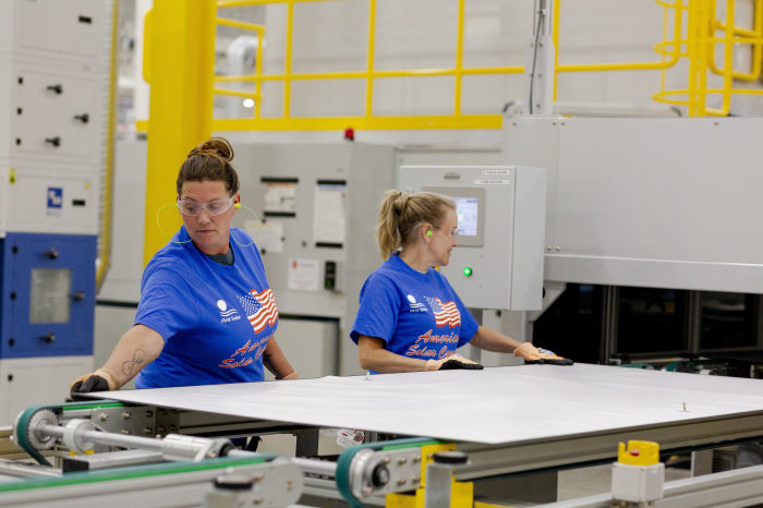 Two workers assembling solar panels in a First Solar manufacturing plant.