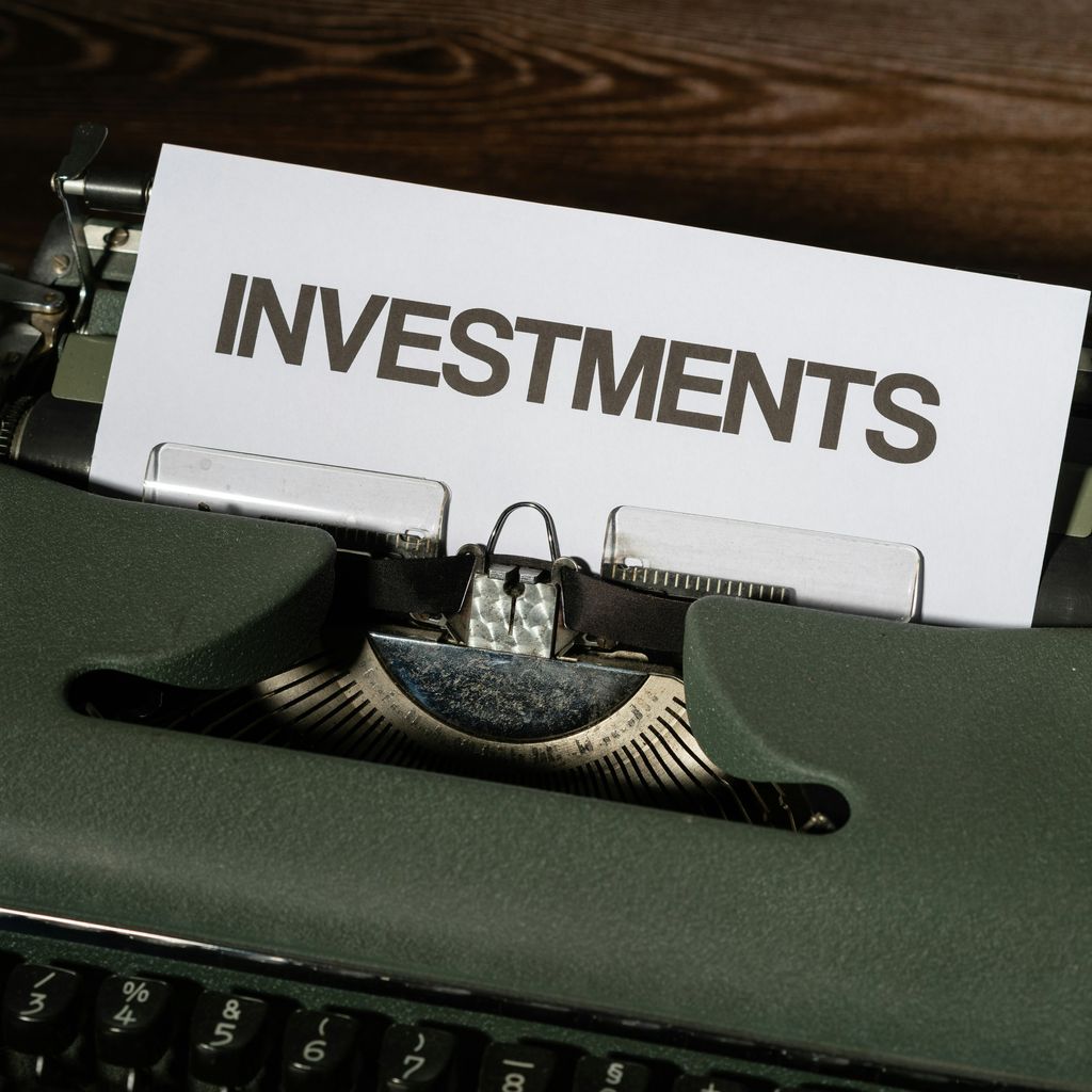 a close up of a typewriter with a paper that reads investments