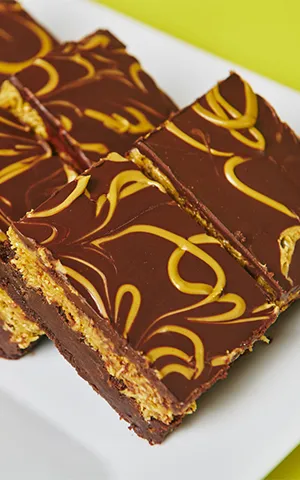 Chocolate dessert bars with caramel swirl on top, arranged on a white plate.