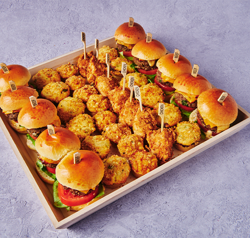 Americana catering tray with mini sliders, fried chicken bites, and bite-sized comfort food appetizers.