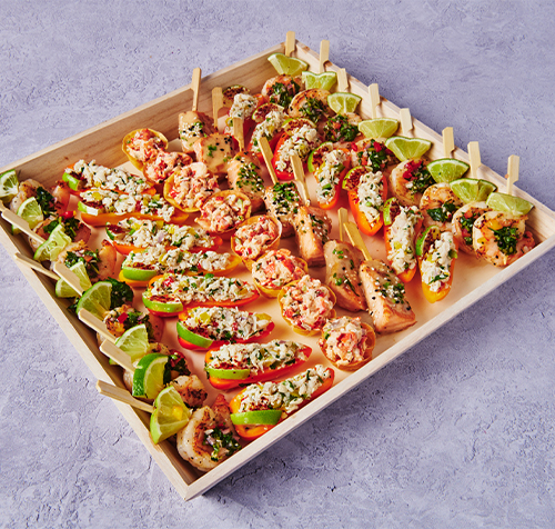 Seafood hors d’oeuvres tray with shrimp, crab bites, cucumber rounds, lime wedges, and fresh herbs.