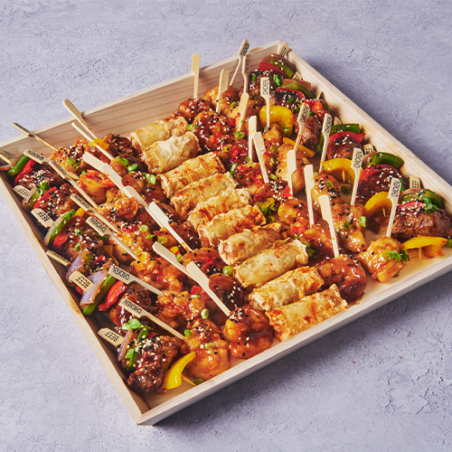 Hunan Royal catering tray with assorted Asian-inspired skewers, dumplings, and vegetable bites.