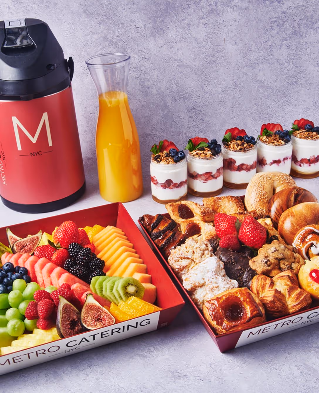 Metro Catering breakfast spread with fresh fruit, pastries, yogurt parfaits, orange juice, coffee, and assorted morning baked goods.