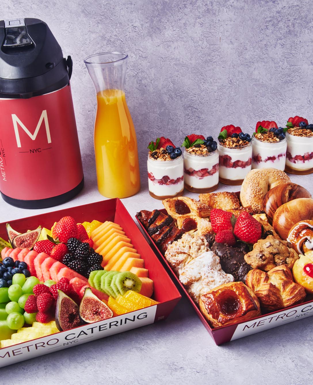 Metro Catering breakfast spread with fresh fruit, pastries, yogurt parfaits, orange juice, coffee, and assorted morning baked goods.