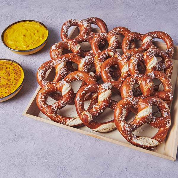 Soft pretzels served with mustard dipping sauces on a platter.