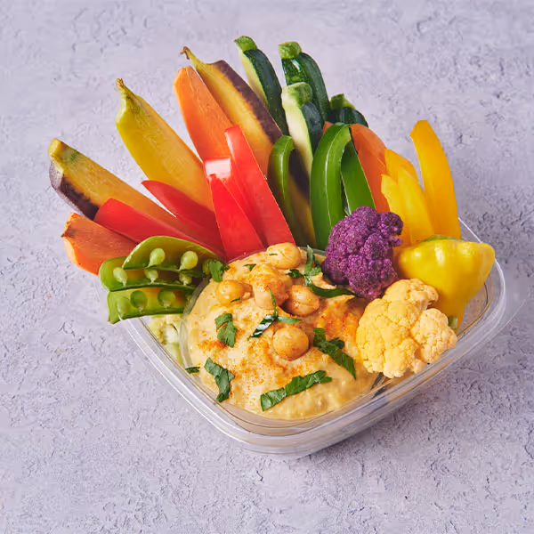 Fresh vegetable crudité platter with hummus and colorful peppers, snap peas, cauliflower, and carrots.