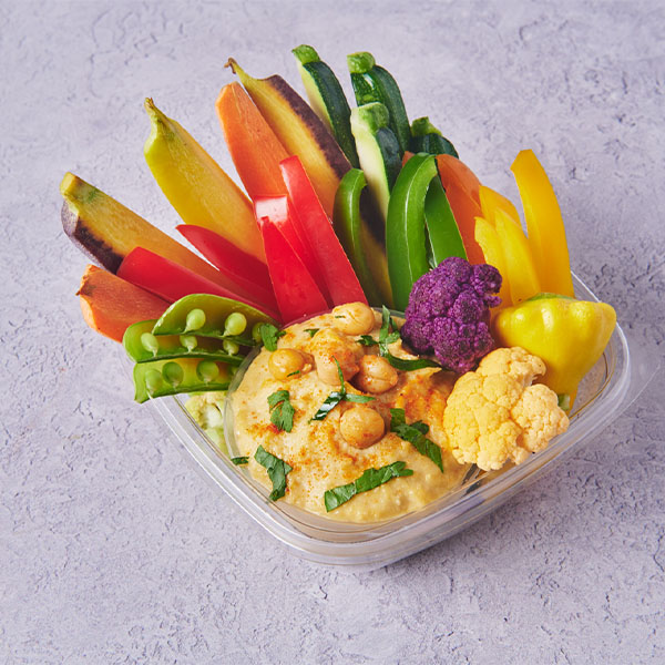 Fresh vegetable crudité platter with hummus and colorful peppers, snap peas, cauliflower, and carrots.