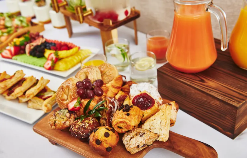 a collection of breakfast foods displaying fresh juices, baked goods and pastries