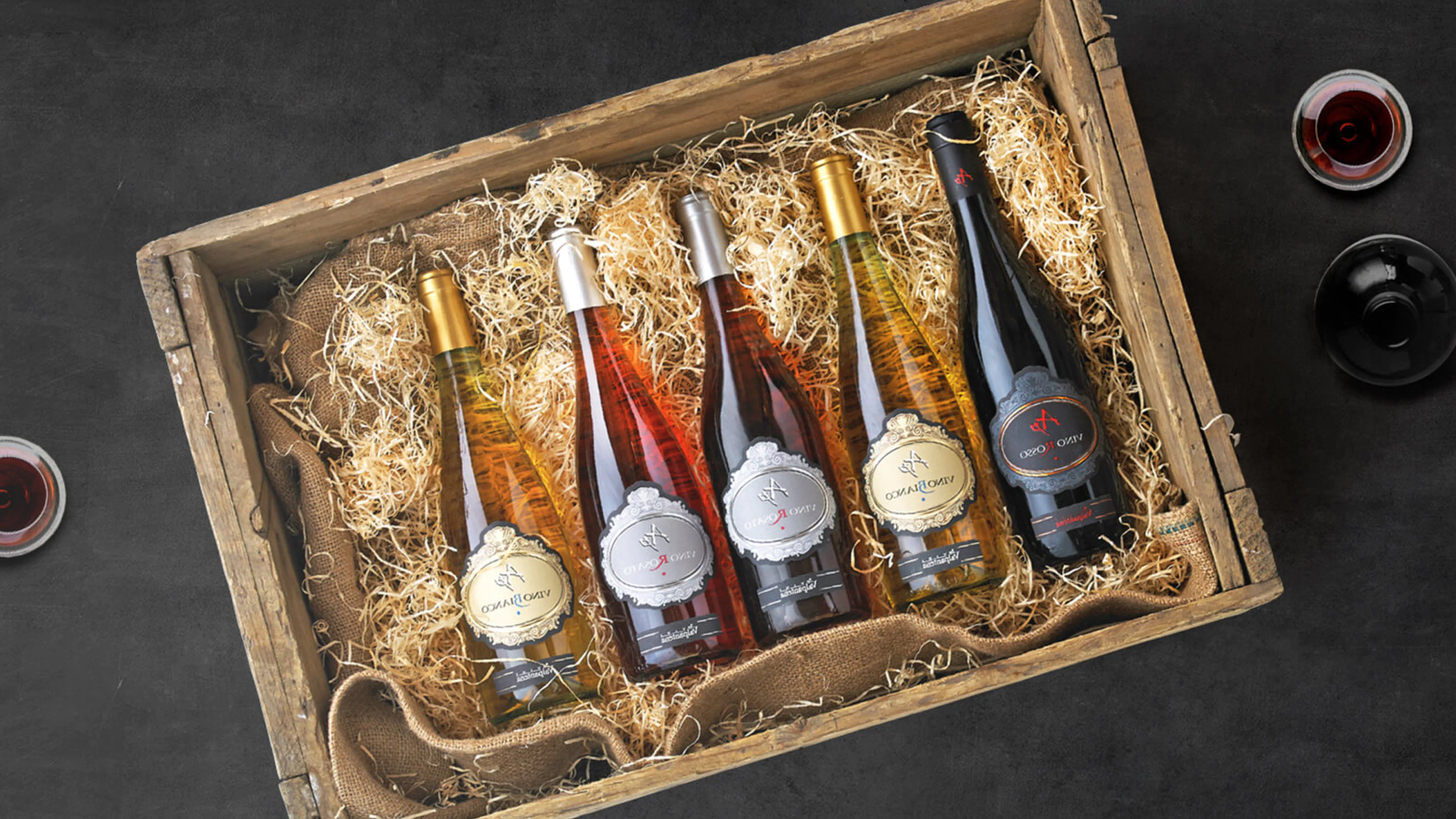 Mood graphic for the SuperBrugsen In-store Digital Wine Universe, presenting curated wine bottles in a rustic crate with surrounding glasses.