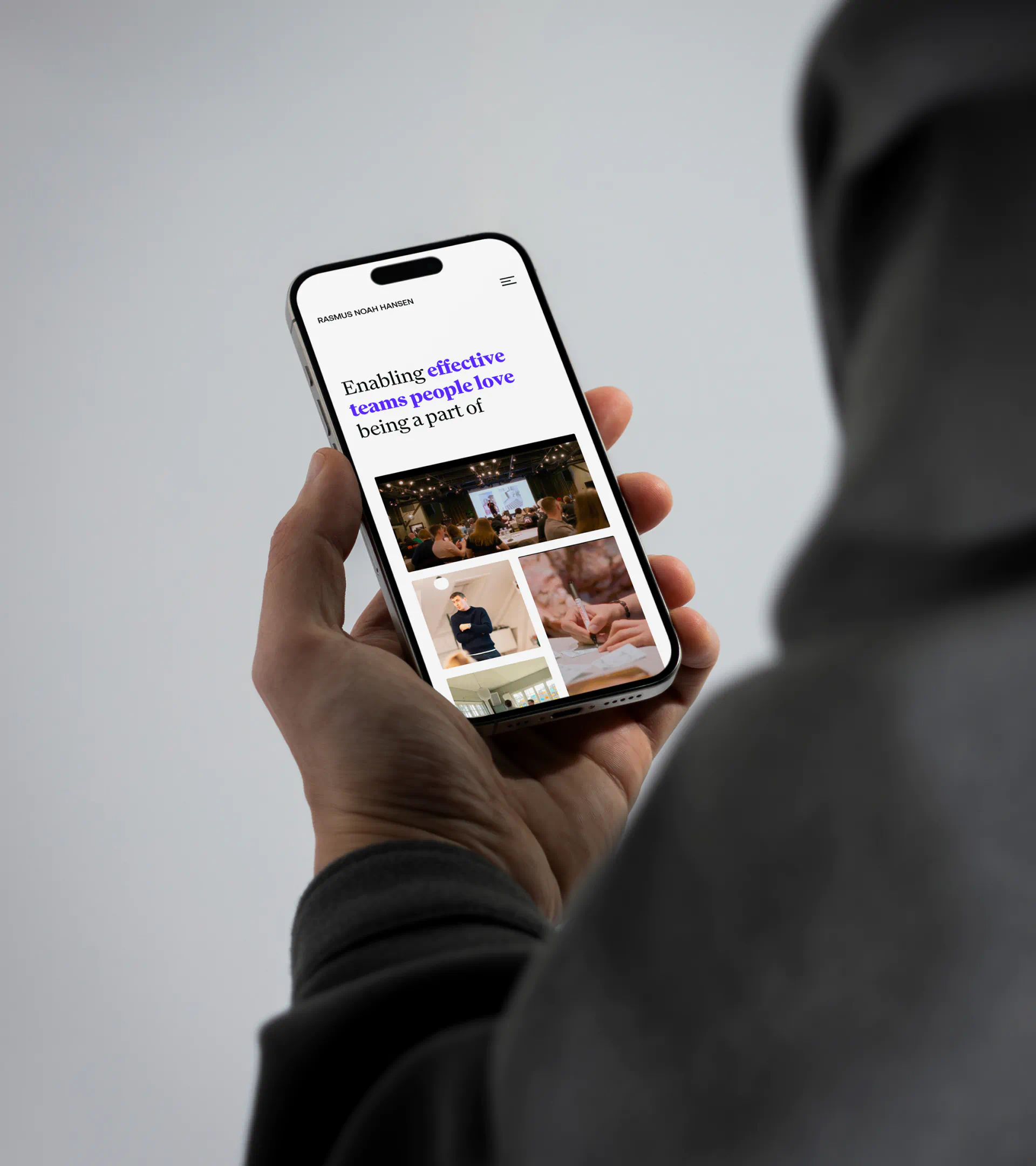 Responsive design mockup of Rasmus Noah Hansen’s website displayed on a smartphone, featuring the headline “Enabling effective teams people love being a part of” with images from workshops and sessions.
