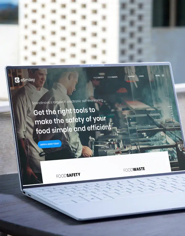 eSmiley website displayed on a laptop in a kitchen setting, showcasing a food safety and food waste platform with strong digital storytelling and a professional interface design.