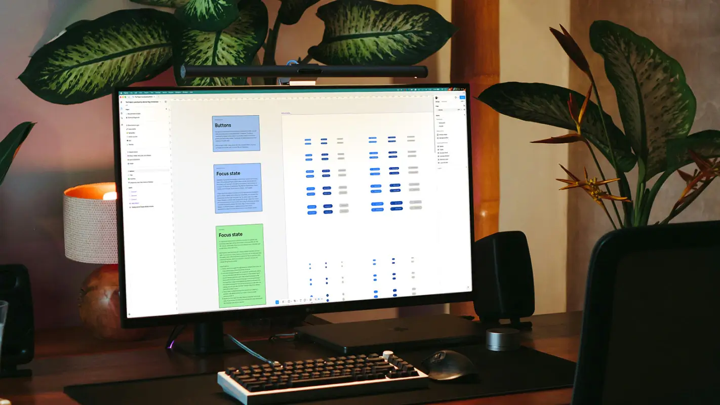 Wide workspace view of The Project Launchpad design system open in Figma, shown on a desktop monitor in a styled studio setting.