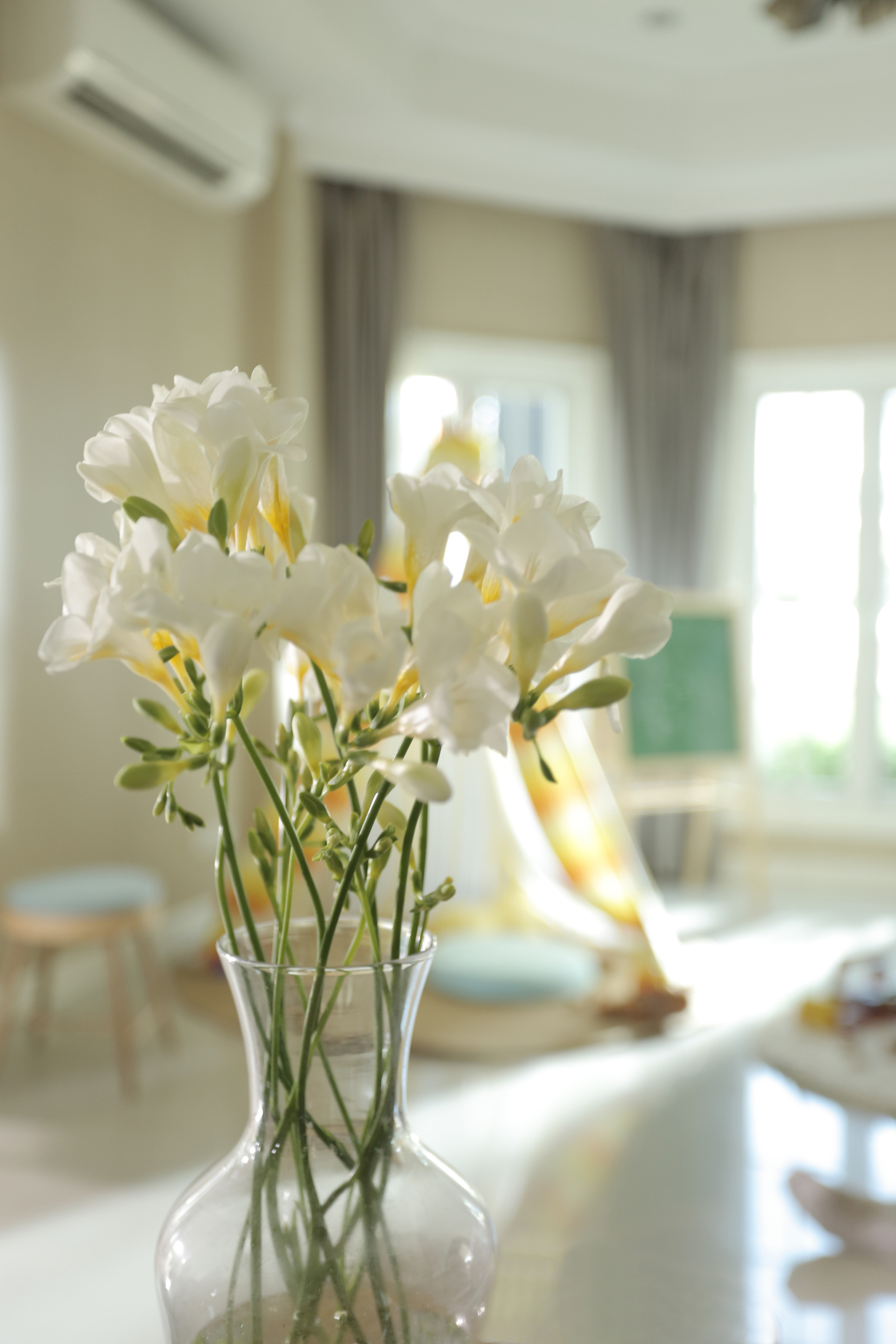 Glass vase with white flowers on table in sunlit aged care or retirement living room