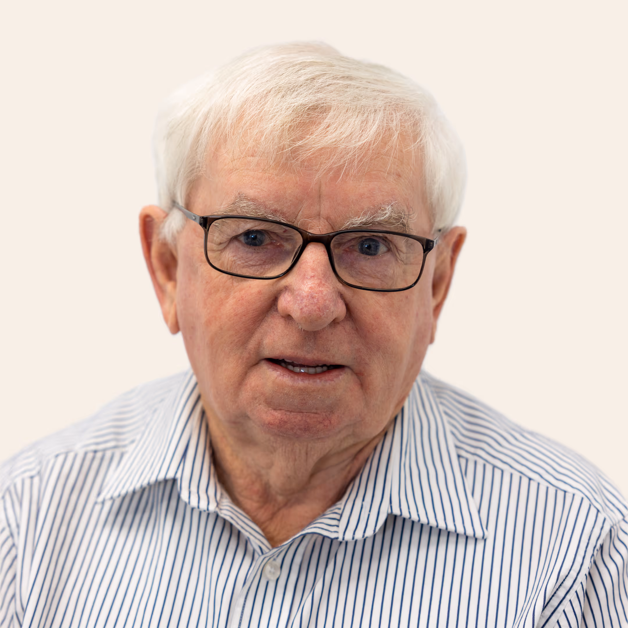 Portrait of Des Caulfield, Director, wearing glasses and striped shirt against neutral background