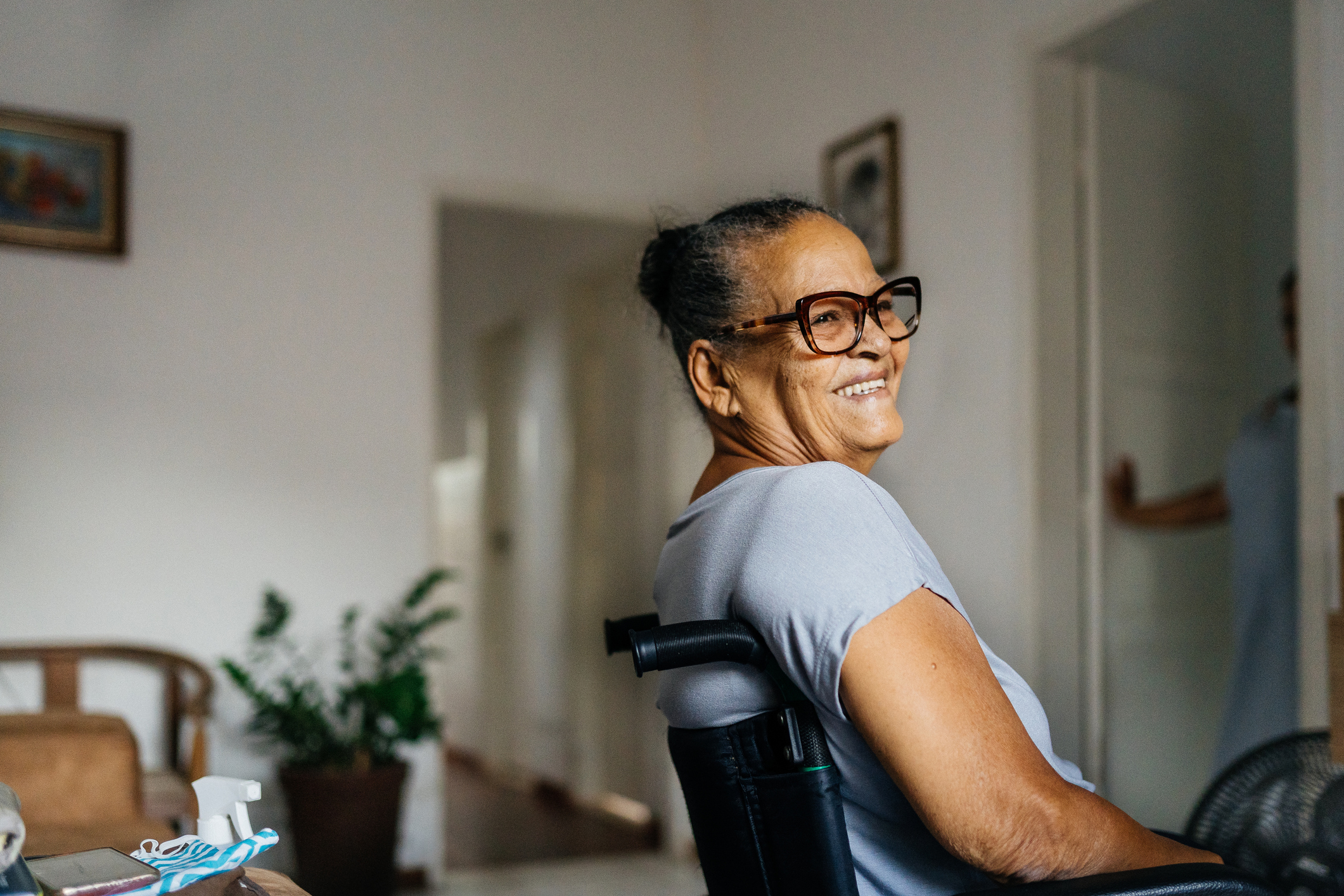 Confident woman in wheelchair smiling in a relaxed home setting, enjoying independence and comfort