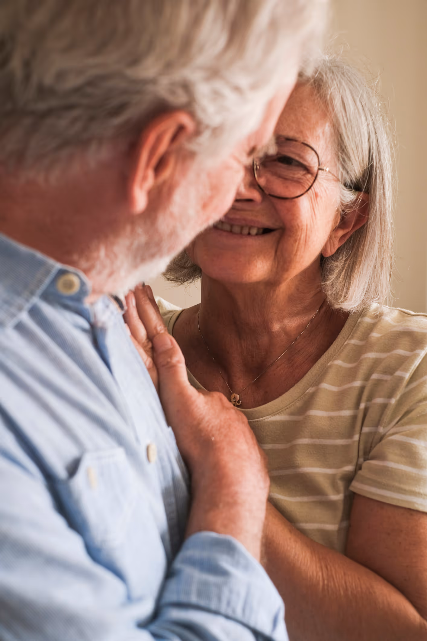Smiling older couple embracing and sharing a loving moment at home, expressing warmth and connection