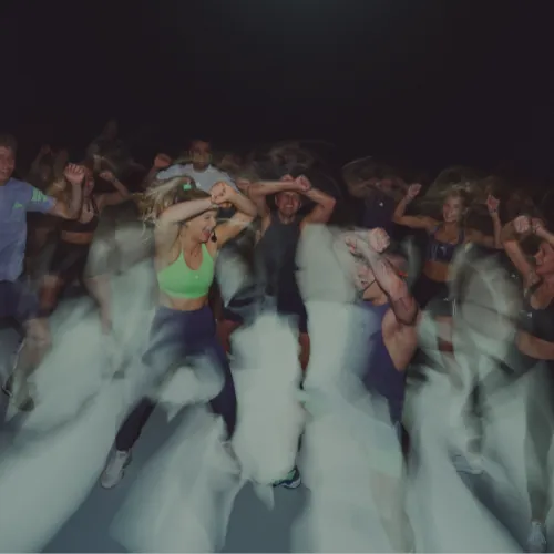 Group of people energetically dancing in a dark setting with blurred motion effects.