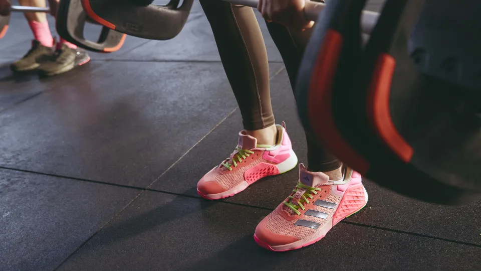 A person lifting a barbell, focus in on their sneakers