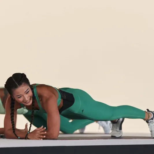Instructor doing a plank and smiling at the audience