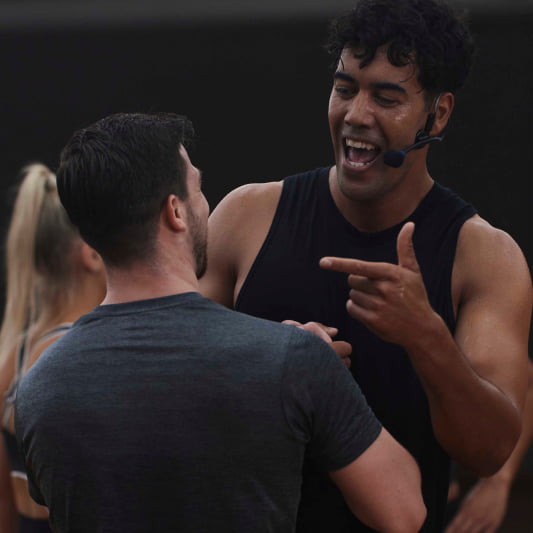 Image of Ben Main, wearning a black singlet, giving encouragement to a class participant