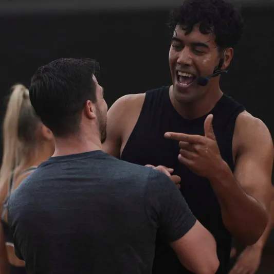 Image of Ben Main, wearning a black singlet, giving encouragement to a class participant