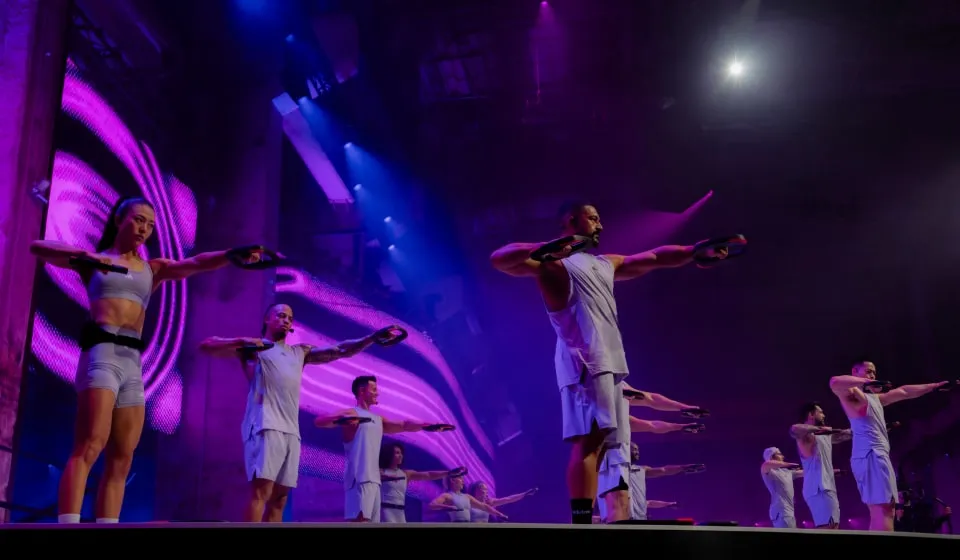 Group of Les Mills BodyPump instructors dressed in adidas workout gear demonstrating the workout to an audience