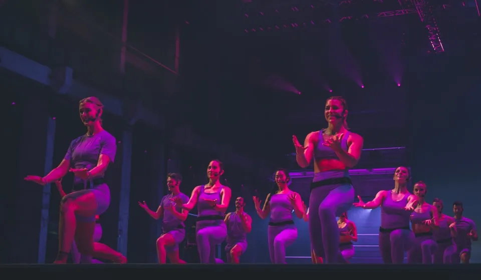 Group of Les Mills BodyBalance instructors dressed in adidas workout gear mid workout on a stage
