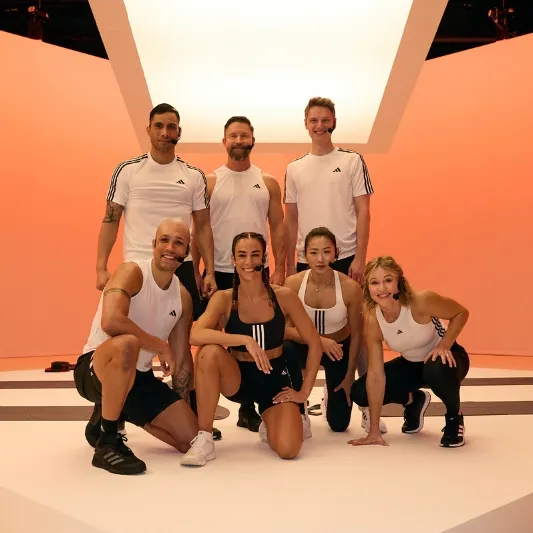 Seven people in athletic wear posing in a fitness studio with a modern, geometric design, commonly used for Les Mills Core sessions.