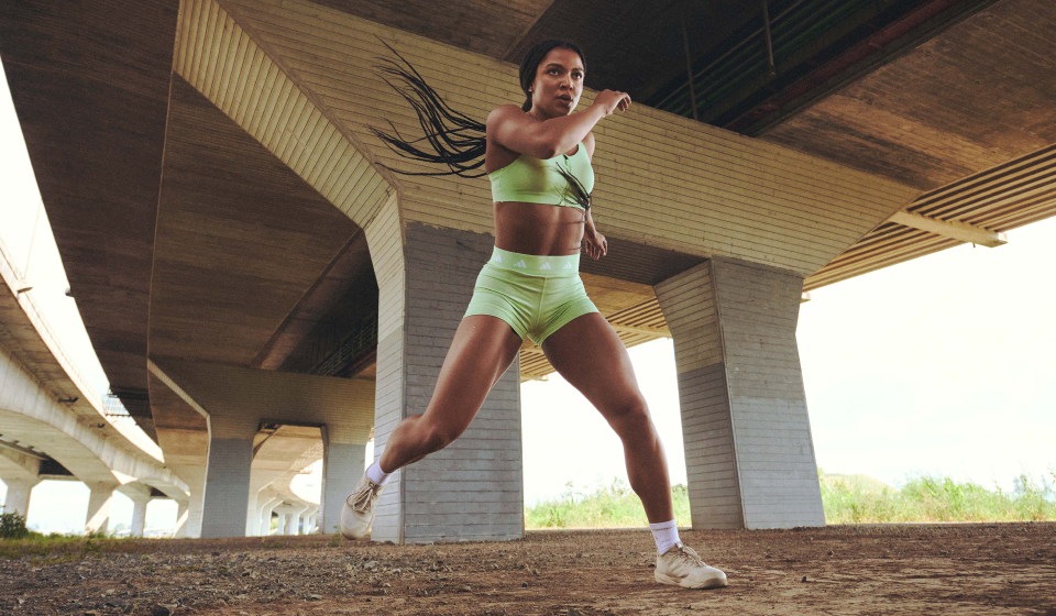 Person in green athletic wear jumps under an overpass