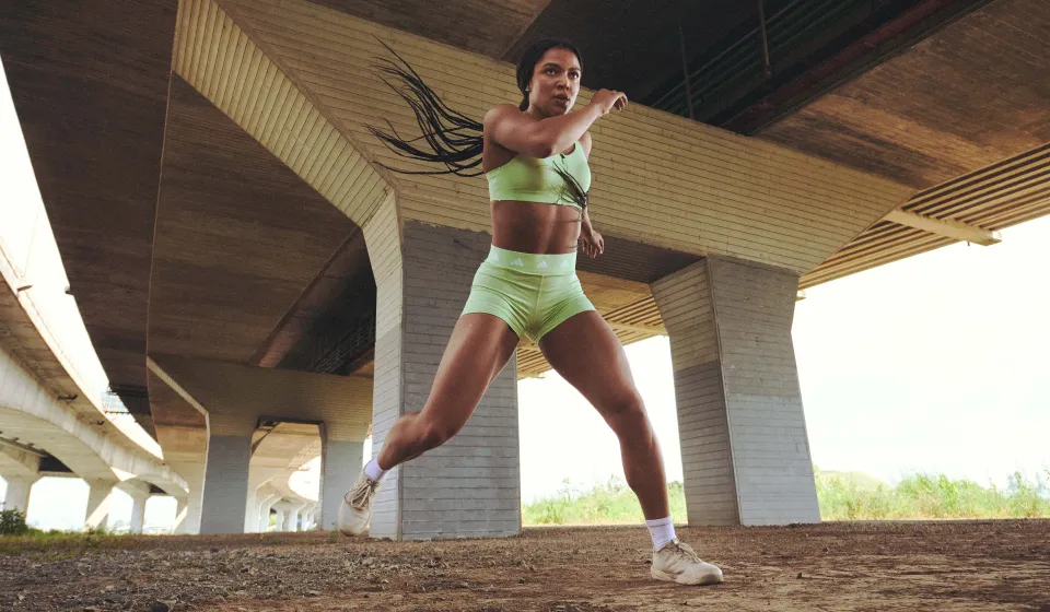 Person in green athletic wear jumps under an overpass