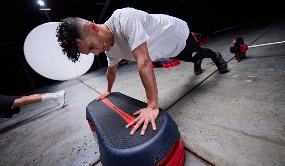 One person wearing a white top doing a push up off a step