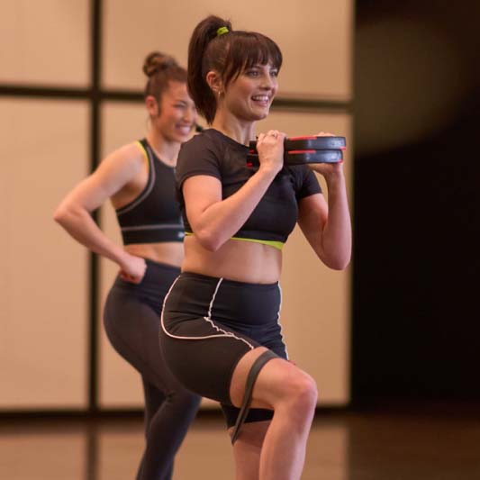 Les Mills Instructor holding two Smartbar plate