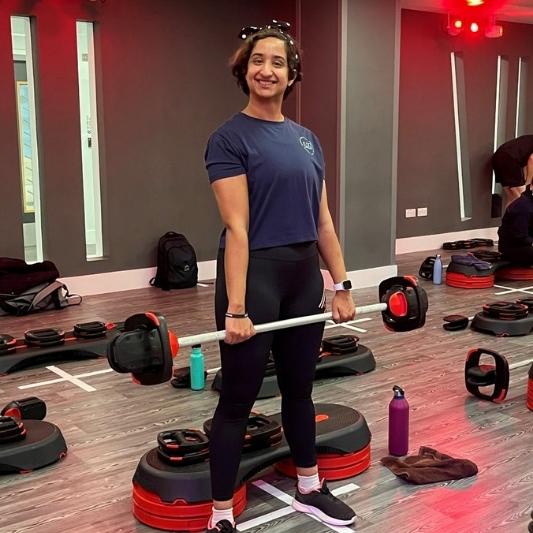 One person stands smiling at the camera holding a barbell