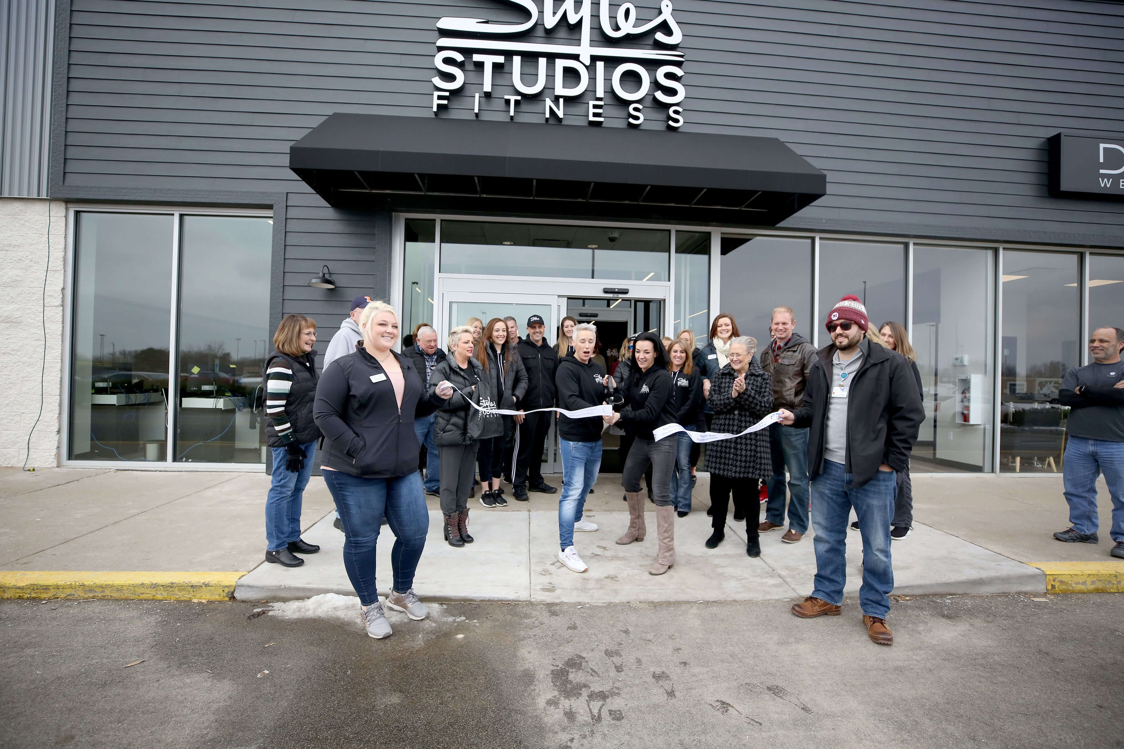 A group of people in black shirts pose in a ribbon cutting event