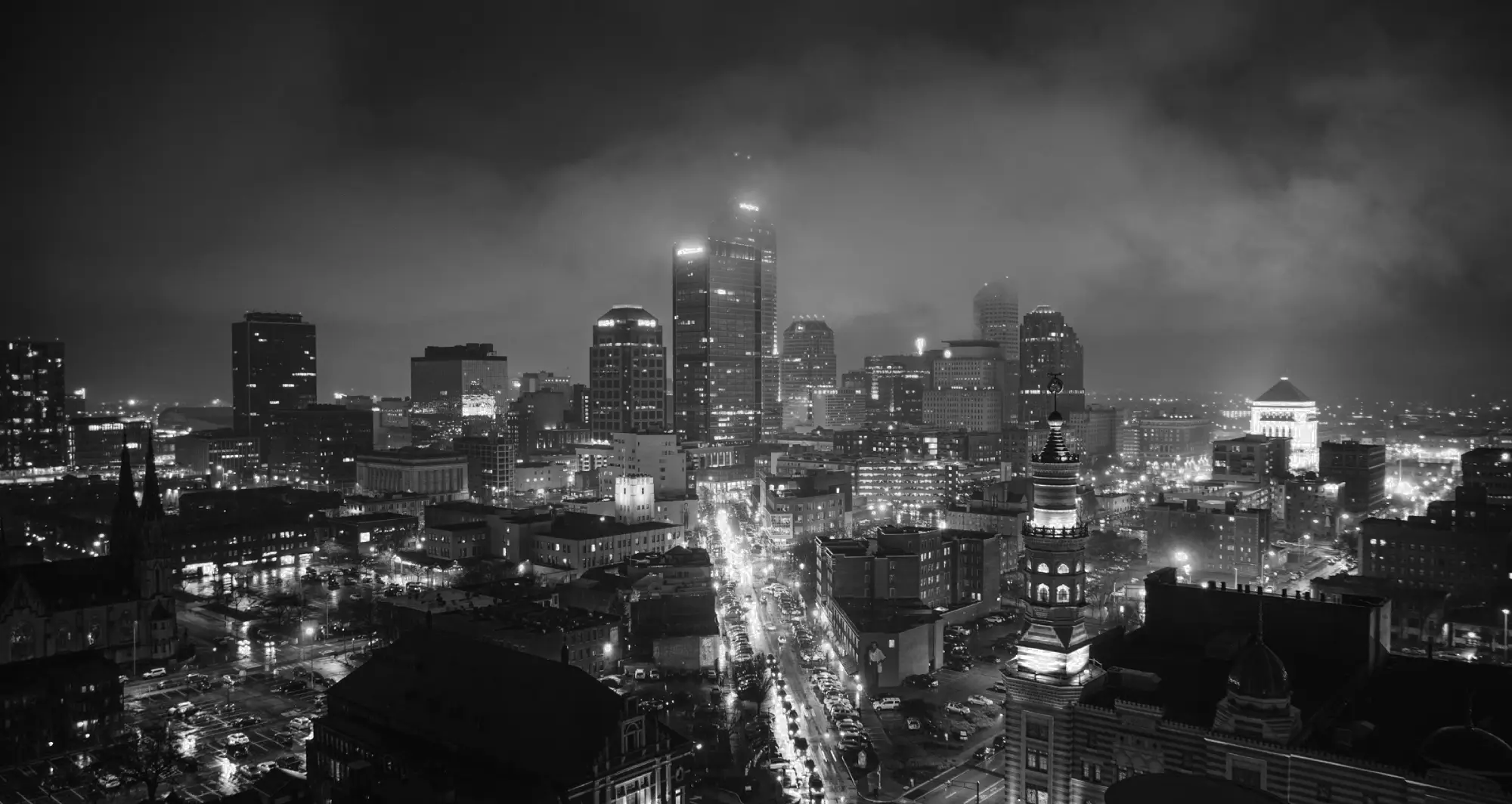Nighttime cityscape of Indianapolis, Indiana, featuring illuminated high-rise buildings