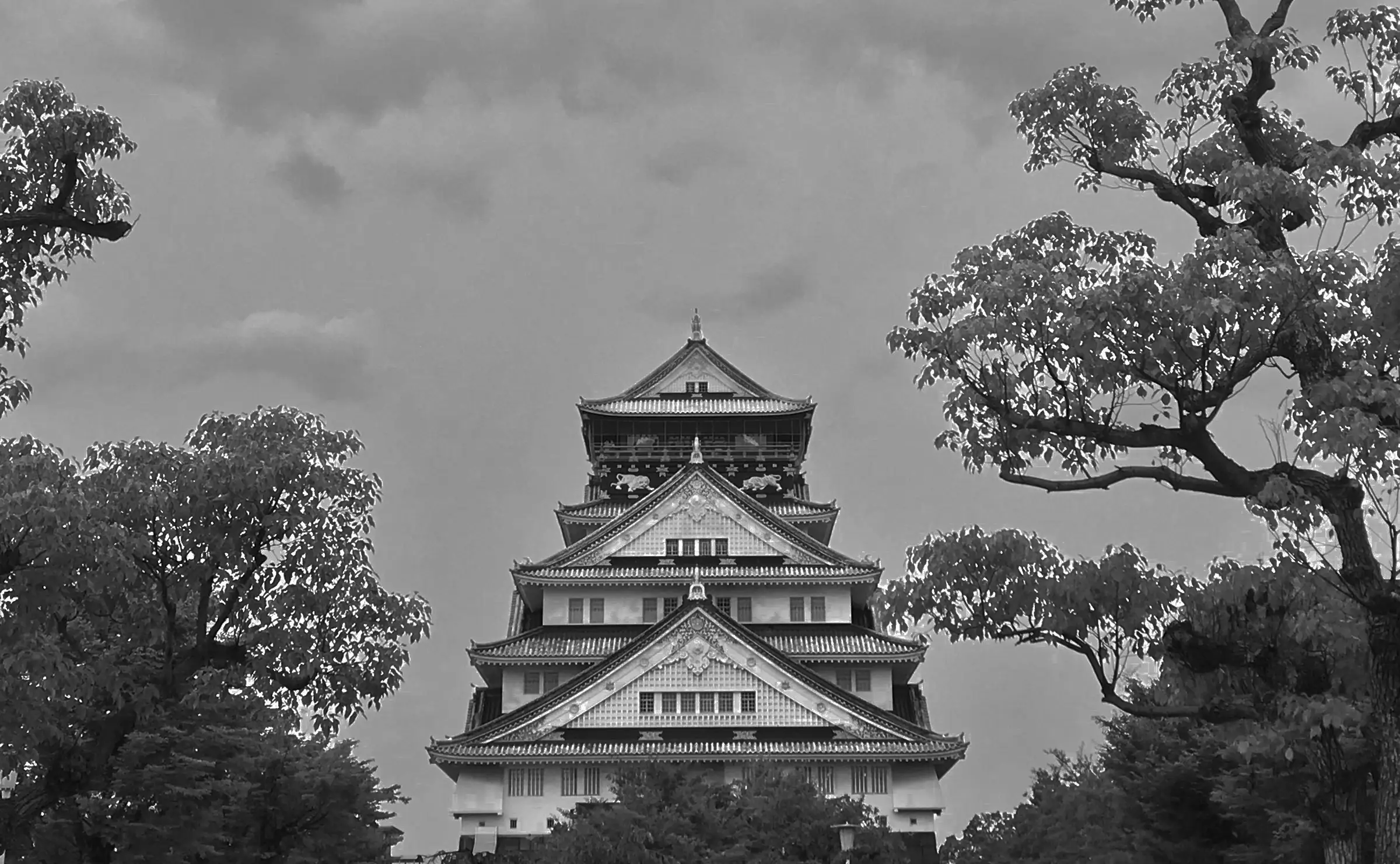 View of Osaka Castle with traditional multi-tiered architecture surrounded by lush trees